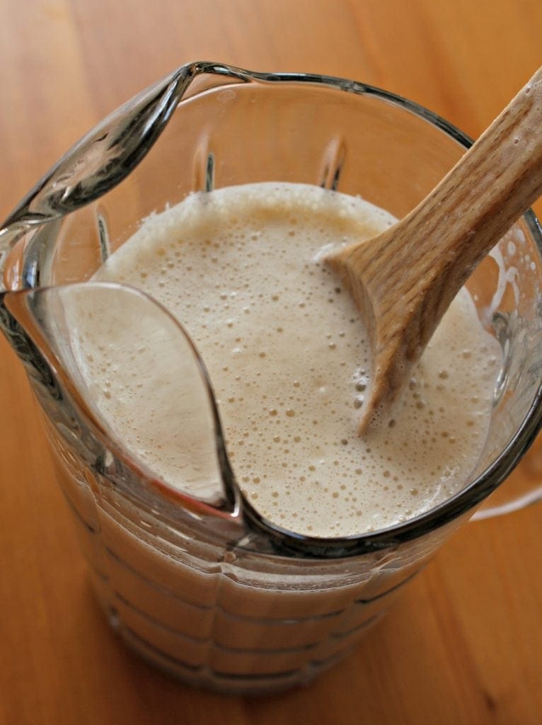 Wooden spoon mixing agua fresca in a pitcher