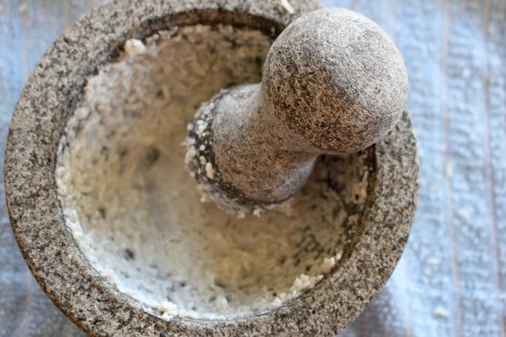 Mixing water and rice in a molcajete.
