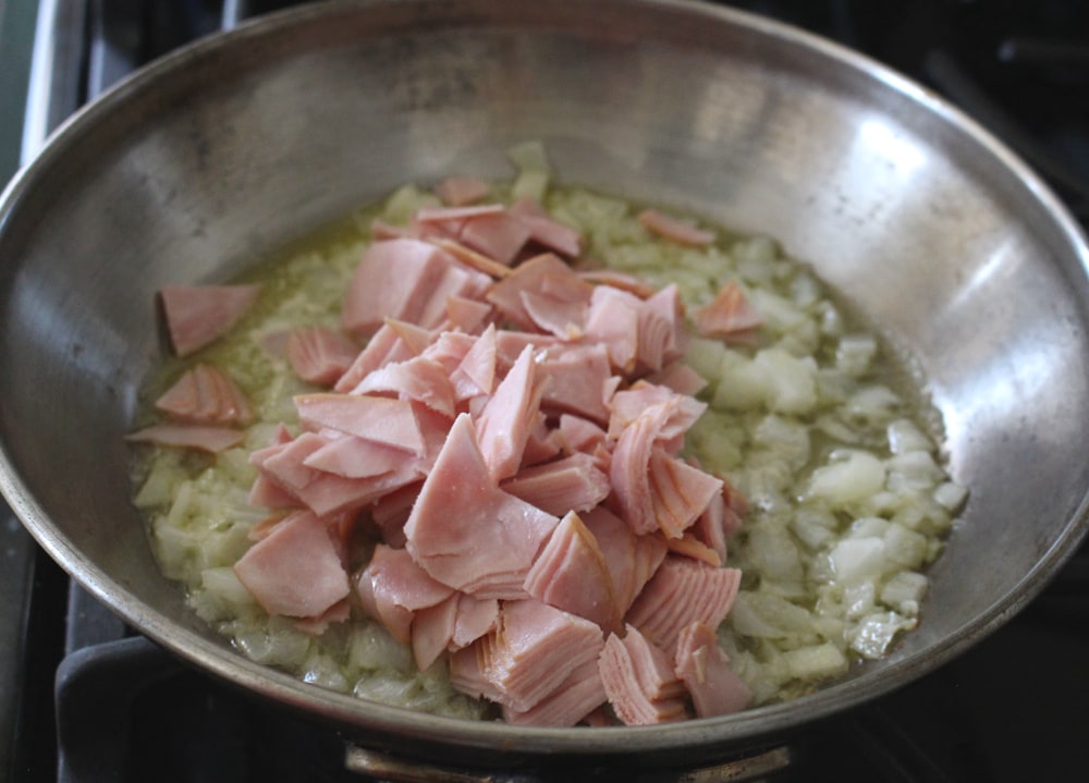 Chopped ham in a skillet over cooked onions