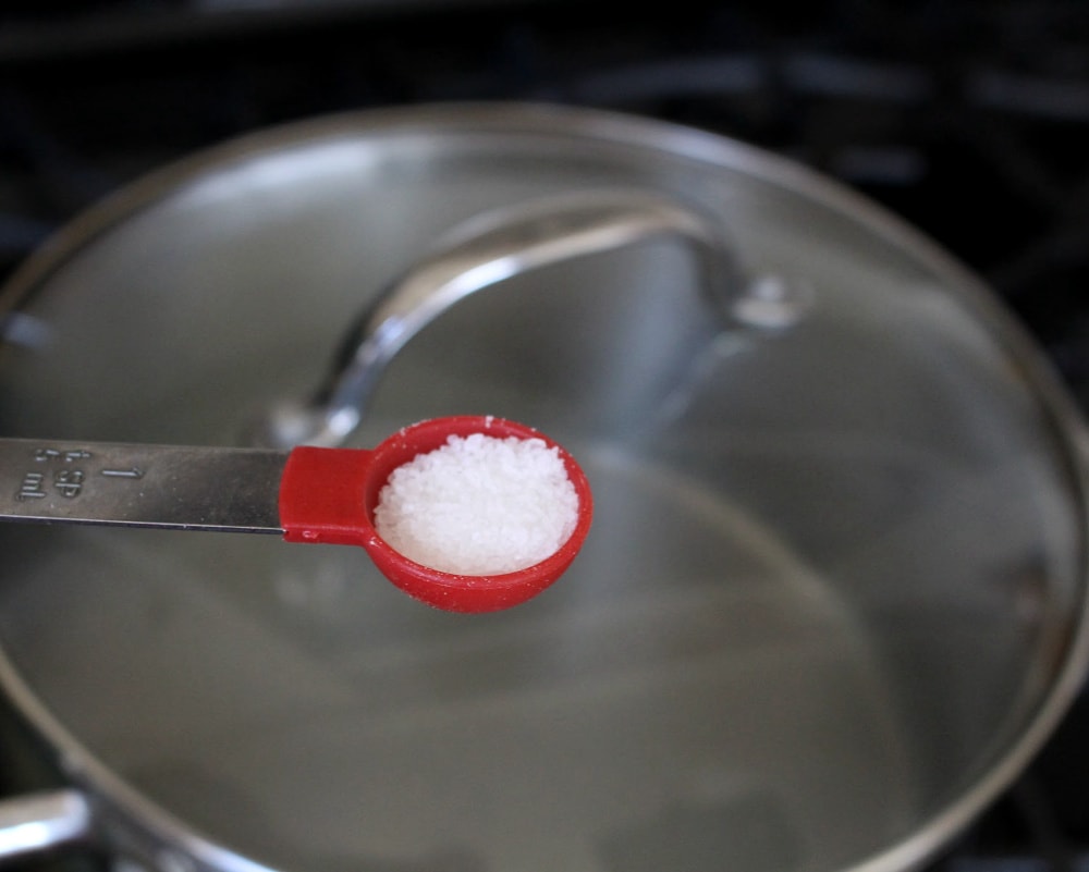 A red teaspoon of salt over a pot with a lid on a stove