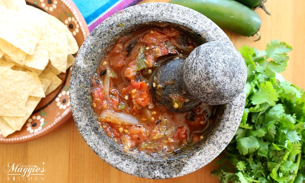 Tomato molcajete salsa surrounded by cilantro, jalapeno, and chips