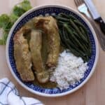 Costillas en Salsa Verde, or Ribs in Mexican Green Salsa, served on a blue plate with rice and green beans.