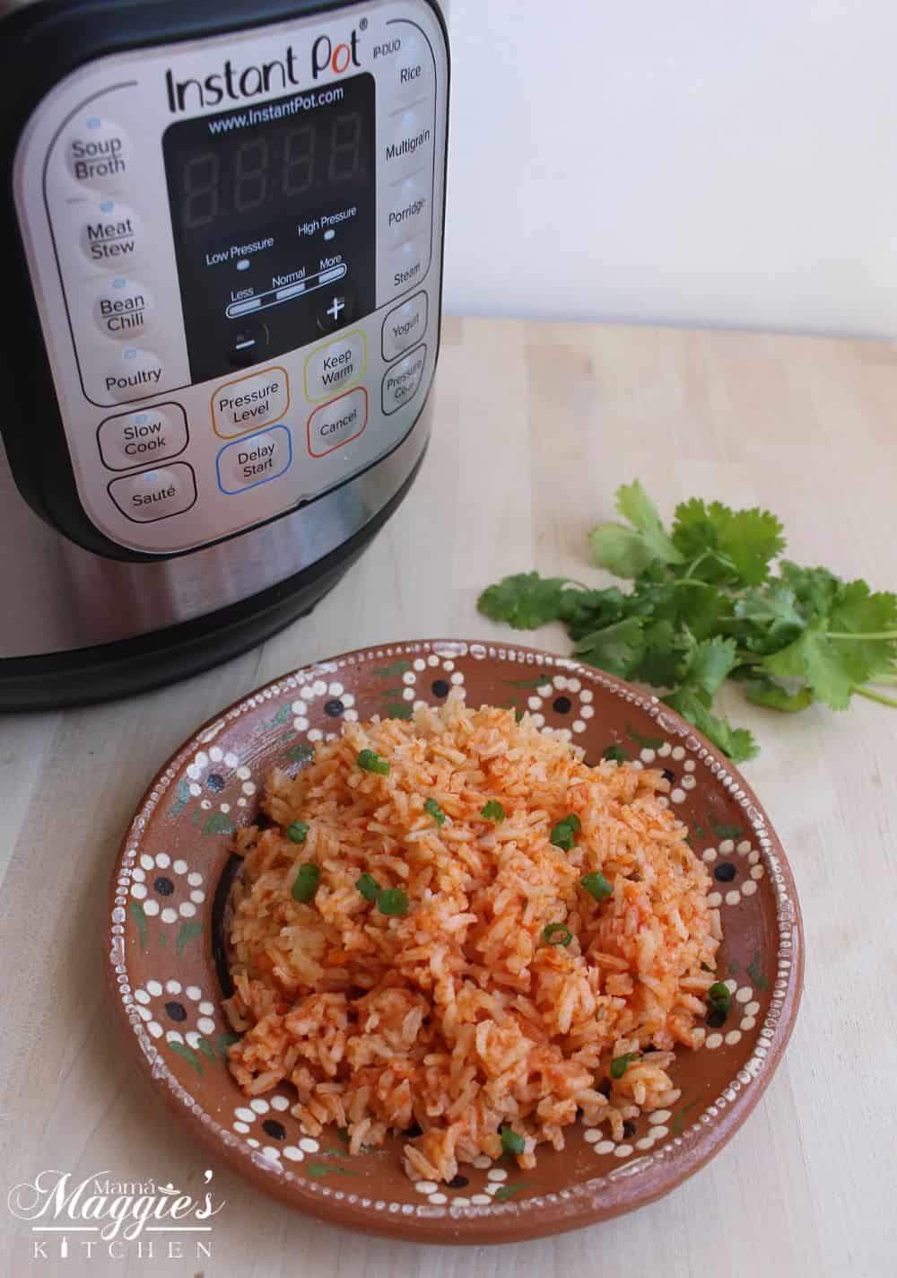 Mexican rice next to an instant pot and cilantro leaves. 