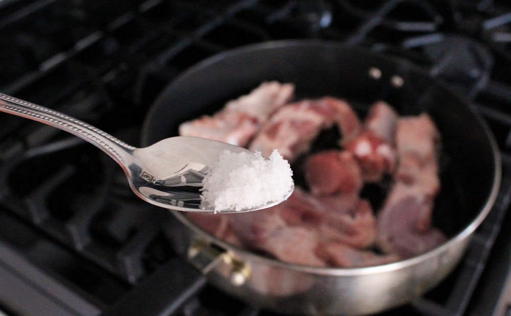 Spoon with sea salt over a black stove. 