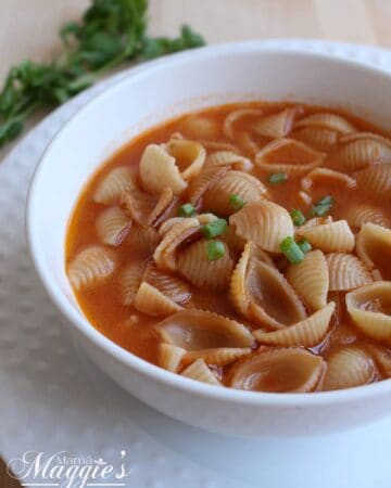 Sopa de Conchas, or Mexican Shell Pasta Soup, in a white bowl and topped with a few slices of green onions.