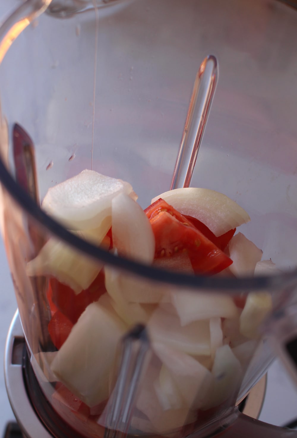 Chopped tomatoes and chopped onions in a blender. 