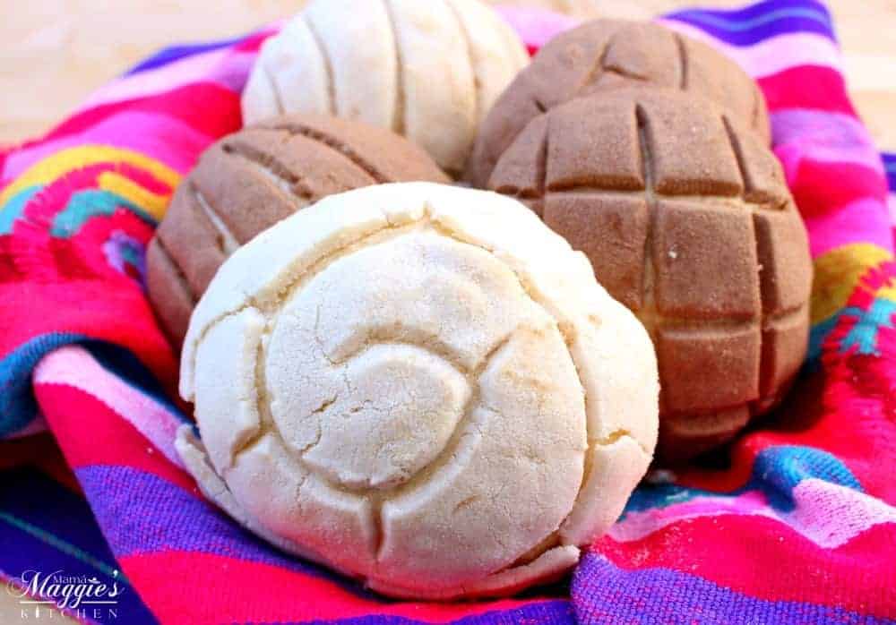 Mexican Sweet Bread Conchas in a decorative and colorful tablecloth.