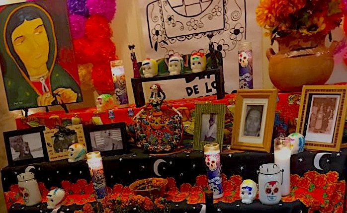 A Day of the Dead altar with skulls, marigolds, candles, and pictures of loved ones. 