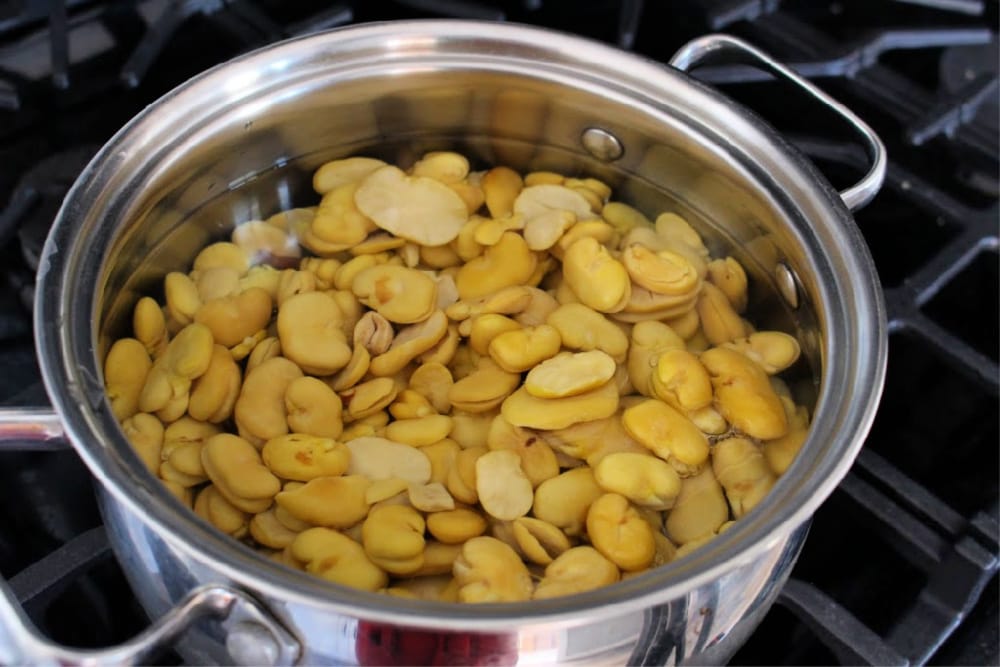 A stock pot with lima beans filled with water.