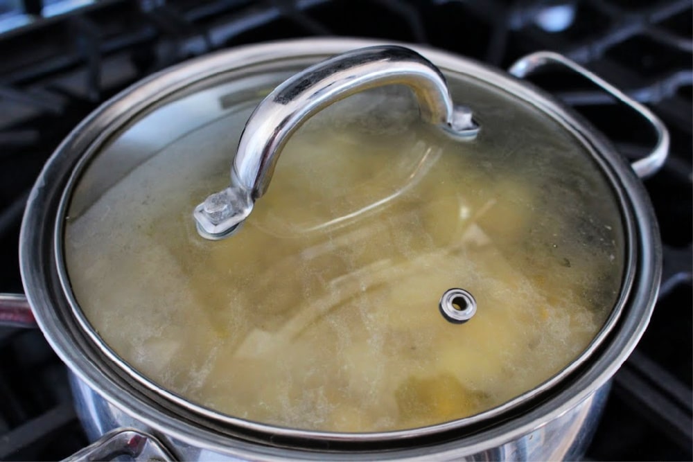 A stock pot with a lid on the stove cooking. 