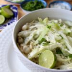 A white bowl of pozole blanco (or chicken pozole) surrounded by the toppings.