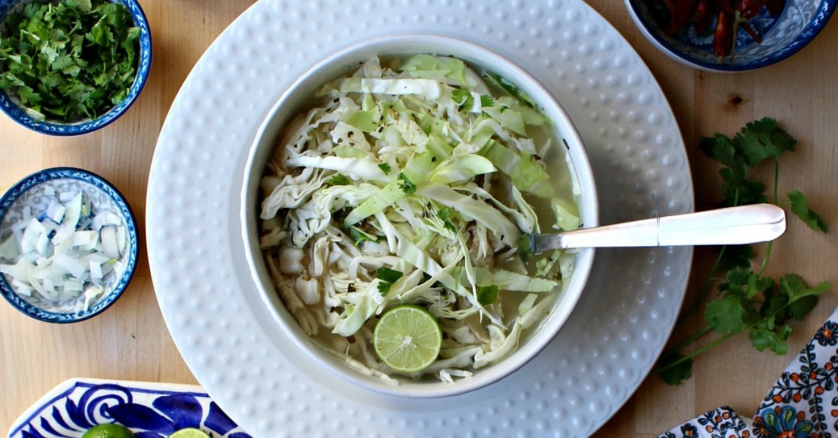 A bowl of Pozole Blanco surrounded by the toppings.