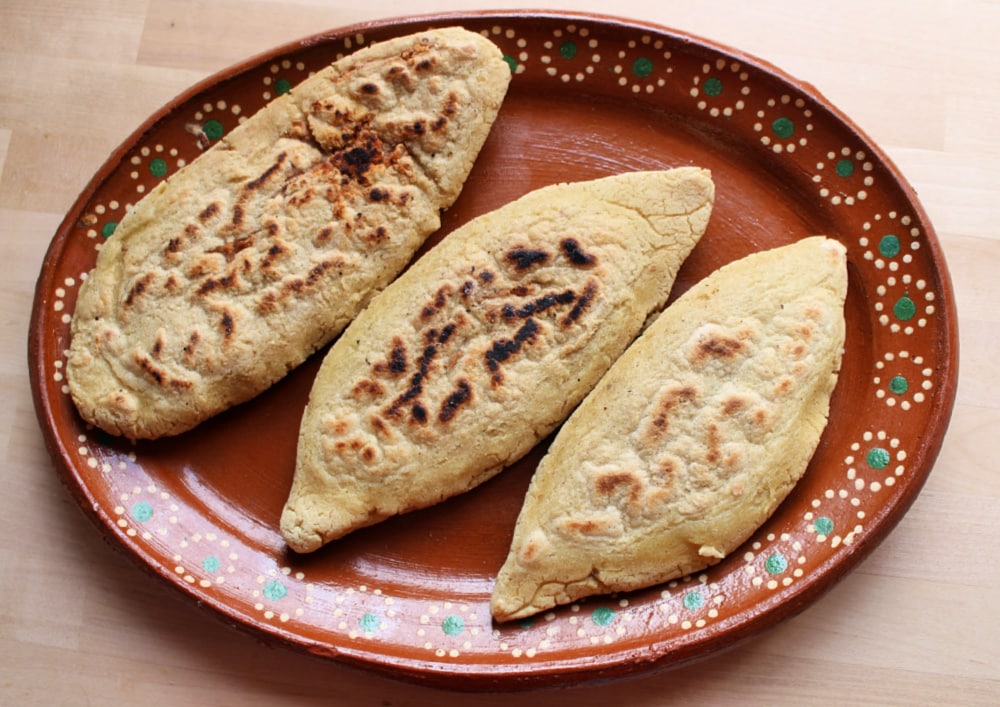 Cooked tlacoyos on a decorative Mexican plate.