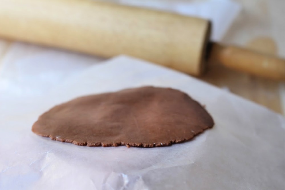 Chocolate topping for conchas rolled out thin on waxing paper next to rolling pin. 