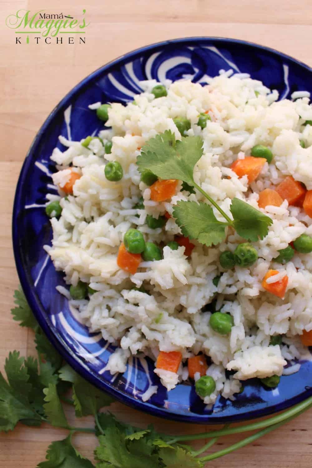 Arroz Blanco (or Mexican White Rice) on a decorative blue plate surrounded and garnished with cilantro leaves.