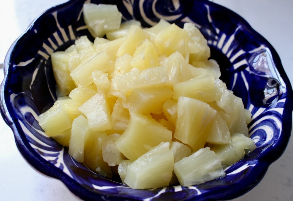 Diced pineapple in a decorative blue plate.