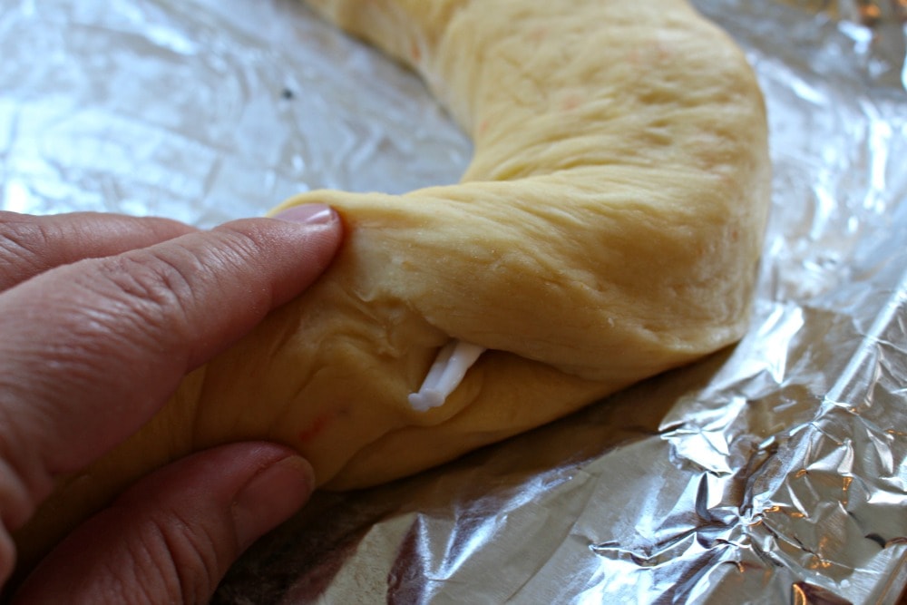Hand hiding the Baby Jesus doll inside the dough.