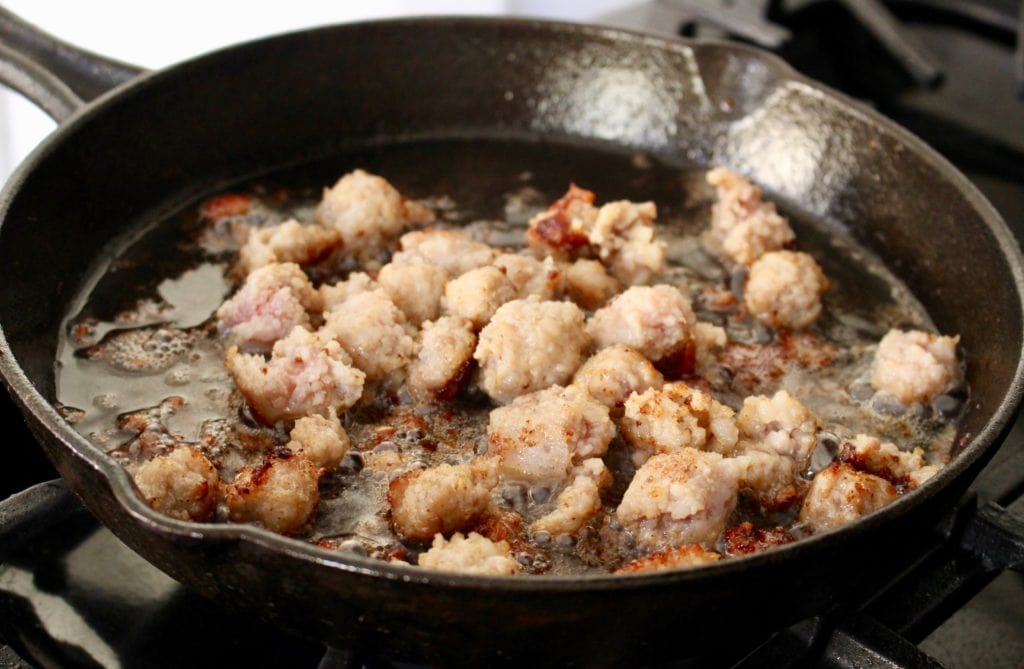 Sausage cooking in a black iron skillet.