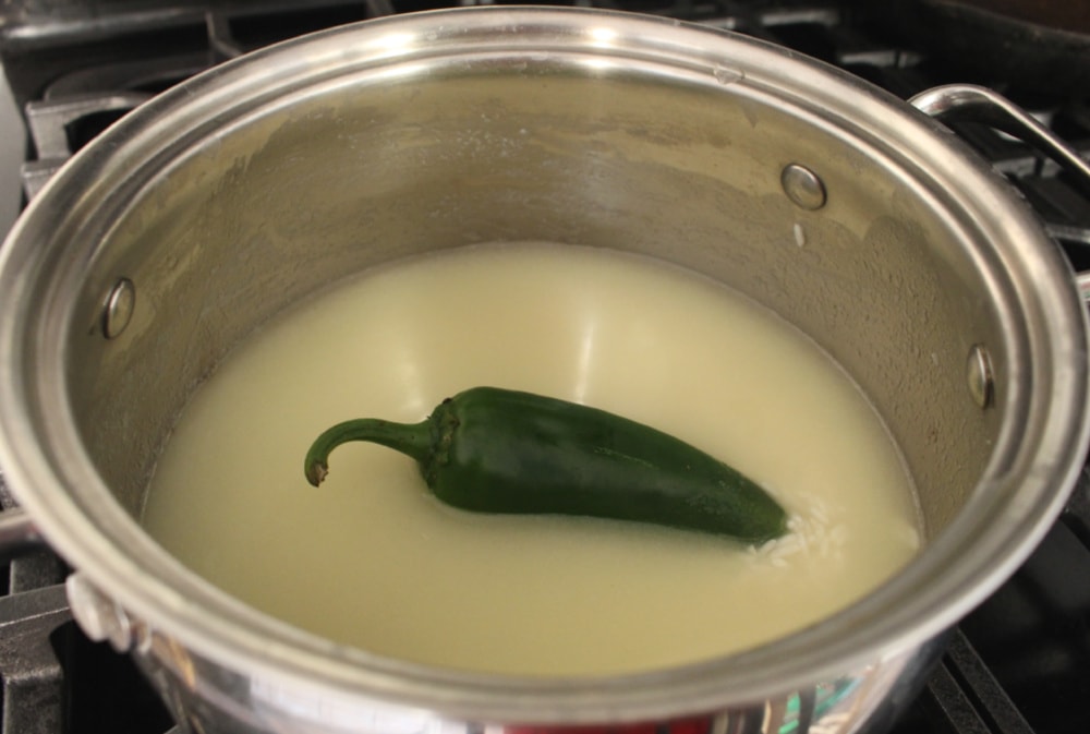Jalapeno pepper in the center of a stock pot filled with rice and water.
