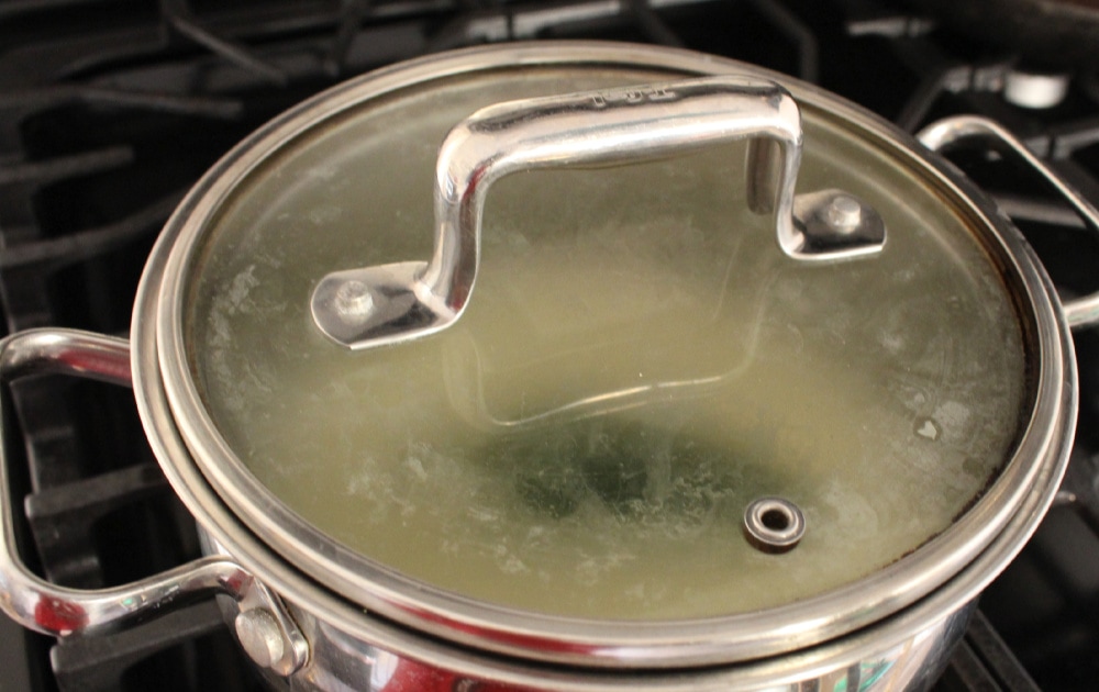 Stock pot with Arroz Blanco cooking on a black stove.