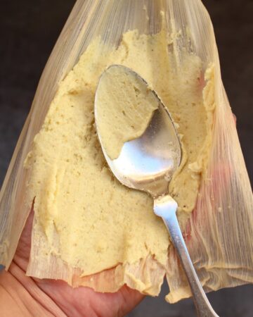 Spoon spreading masa with oil on a corn husk.