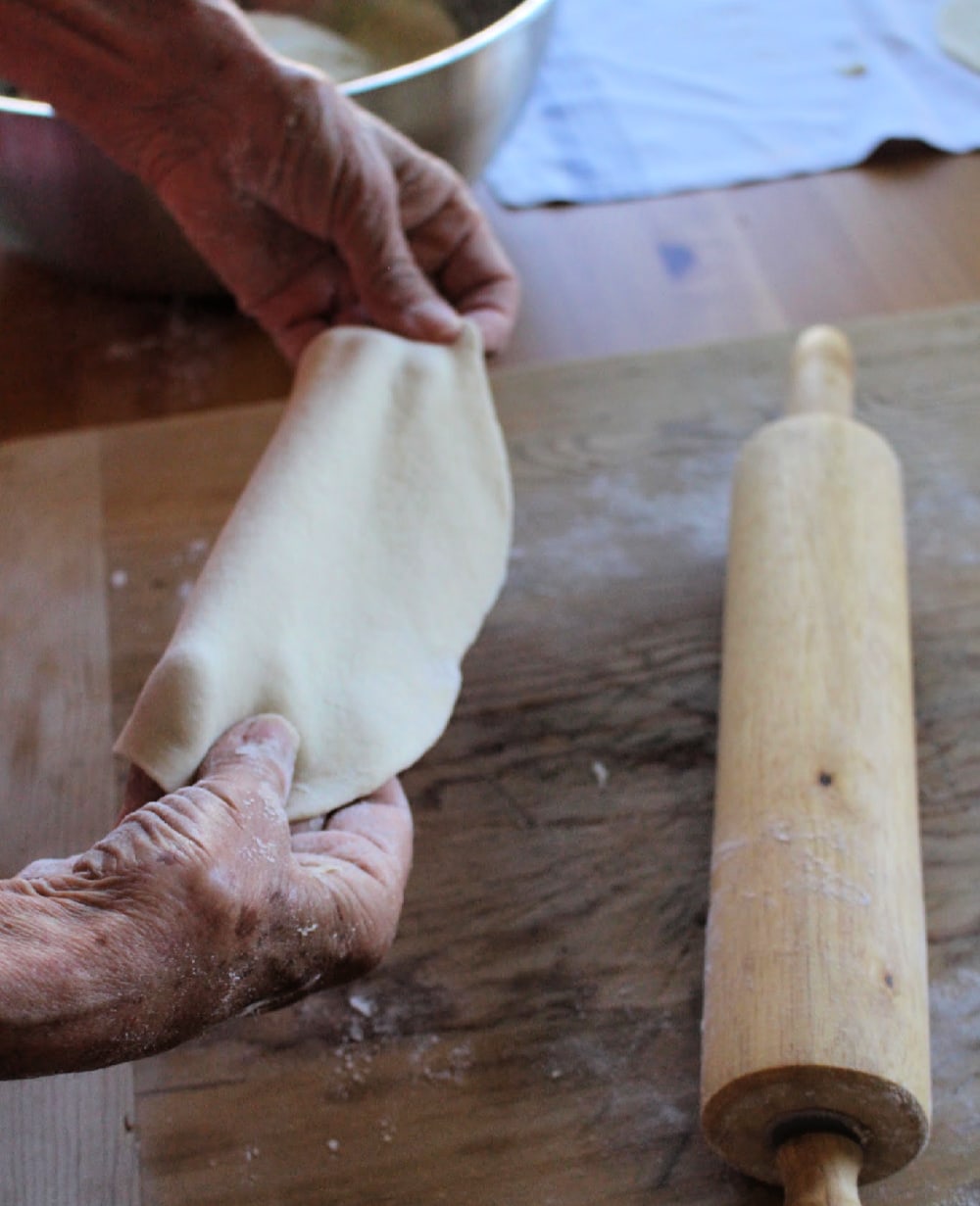 Hands stretching out the Buñuelos dough. 