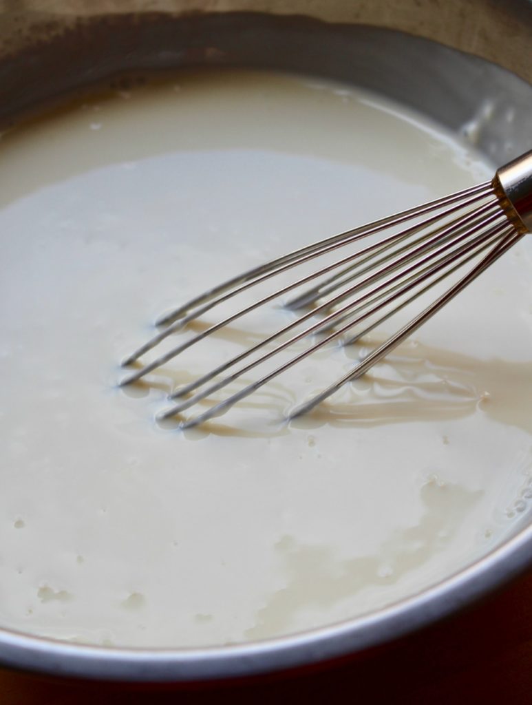 Whisk in a metal bowl beating a creamy dressing. 