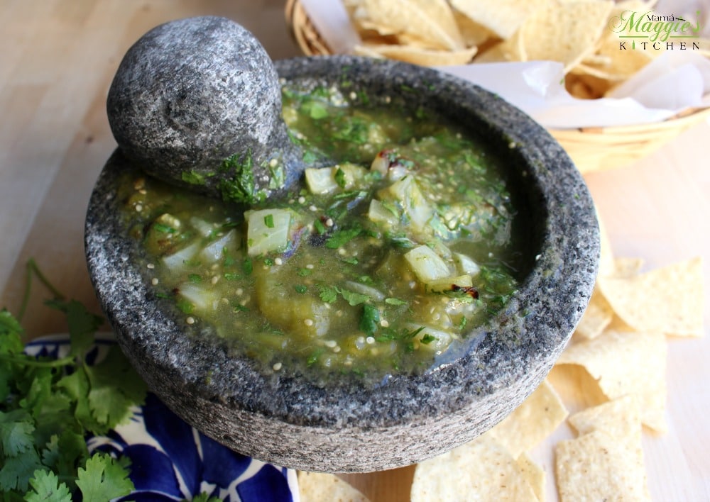 Molcajete Salsa Verde surrounded by corn tortilla chips and green cilantro.