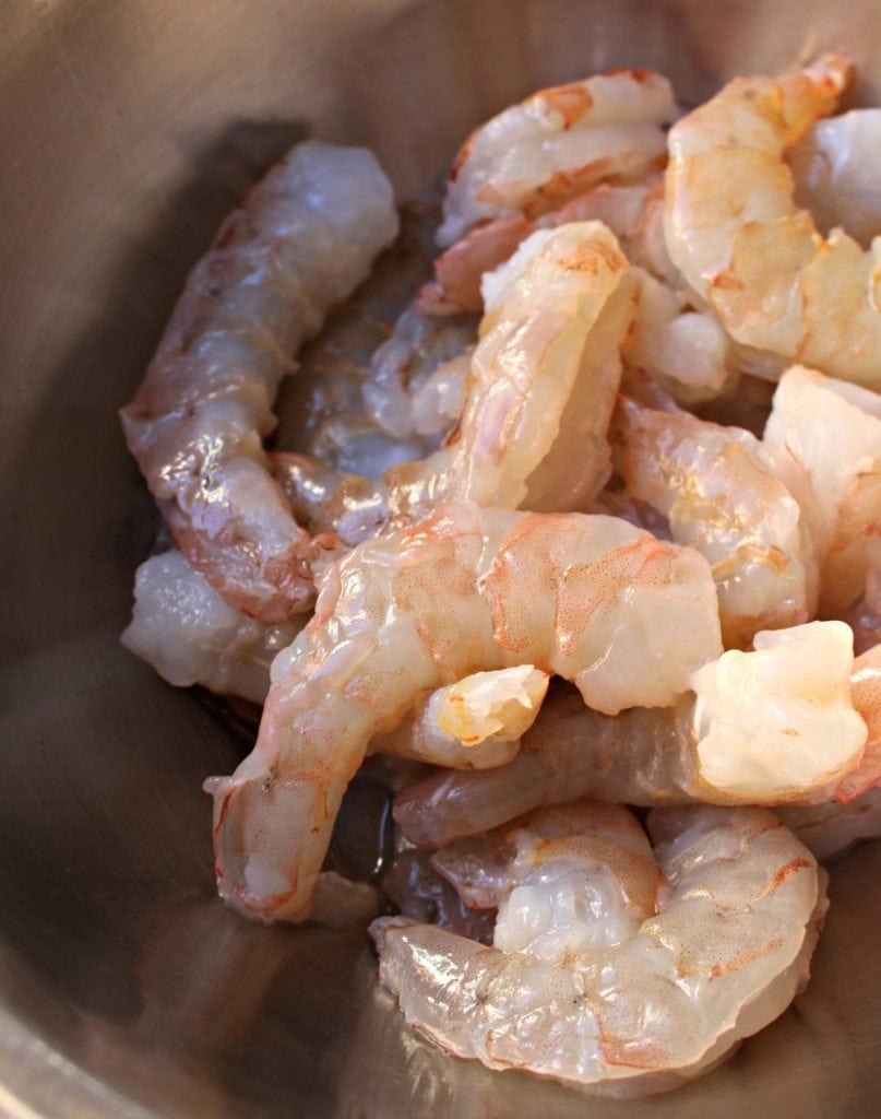 Raw shrimp in a metal bowl. 