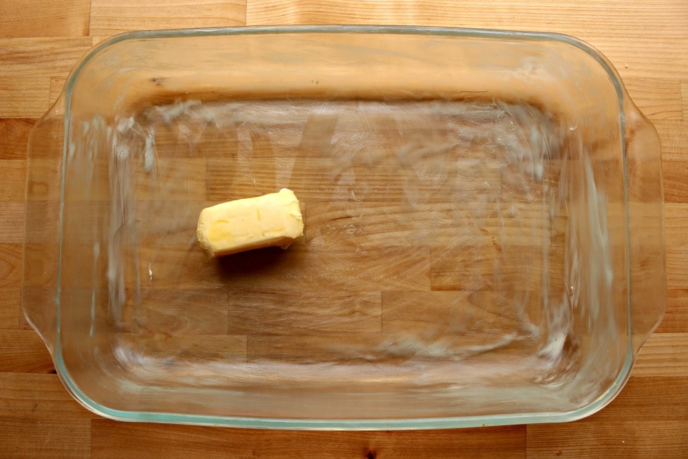Half a stick of butter buttering up the sides of a glass container.
