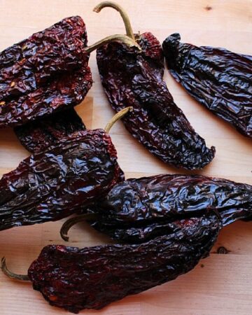 Dried chile ancho on a wooden surface.