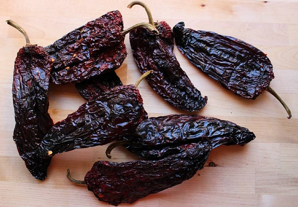 Dried chile ancho on a wooden surface.
