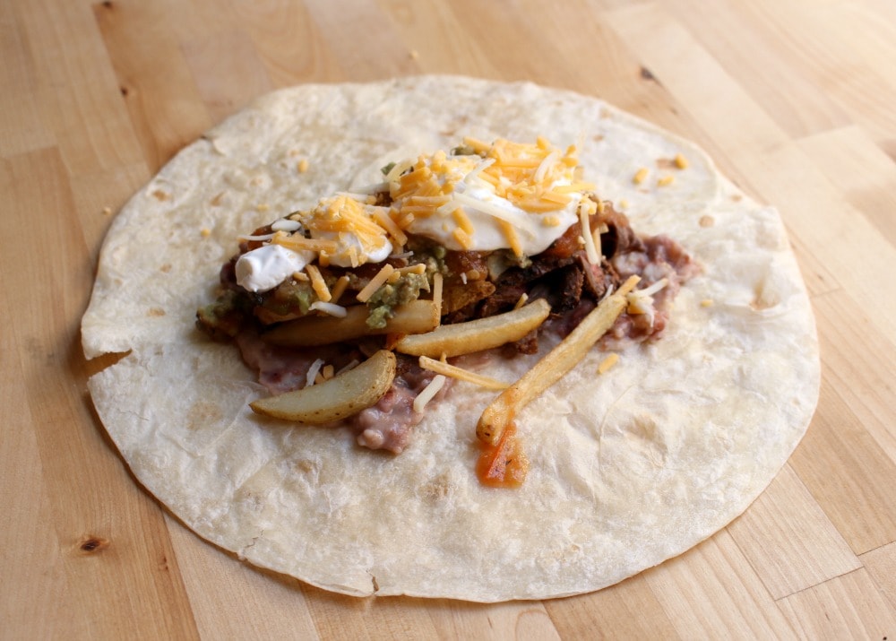 A burrito-sized tortilla with all the fillings for the California Burrito in the center.