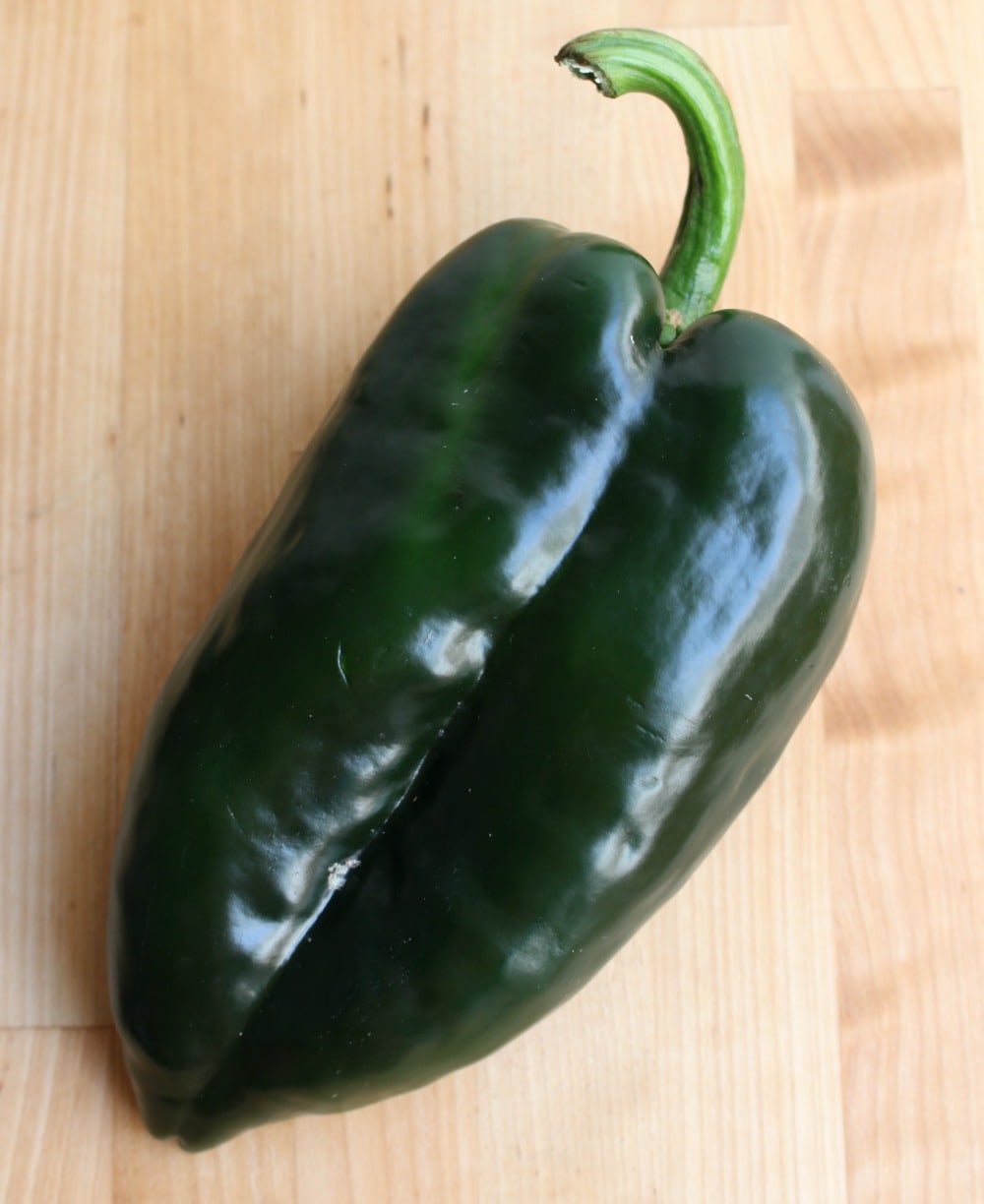 A poblano pepper on a wooden surface.