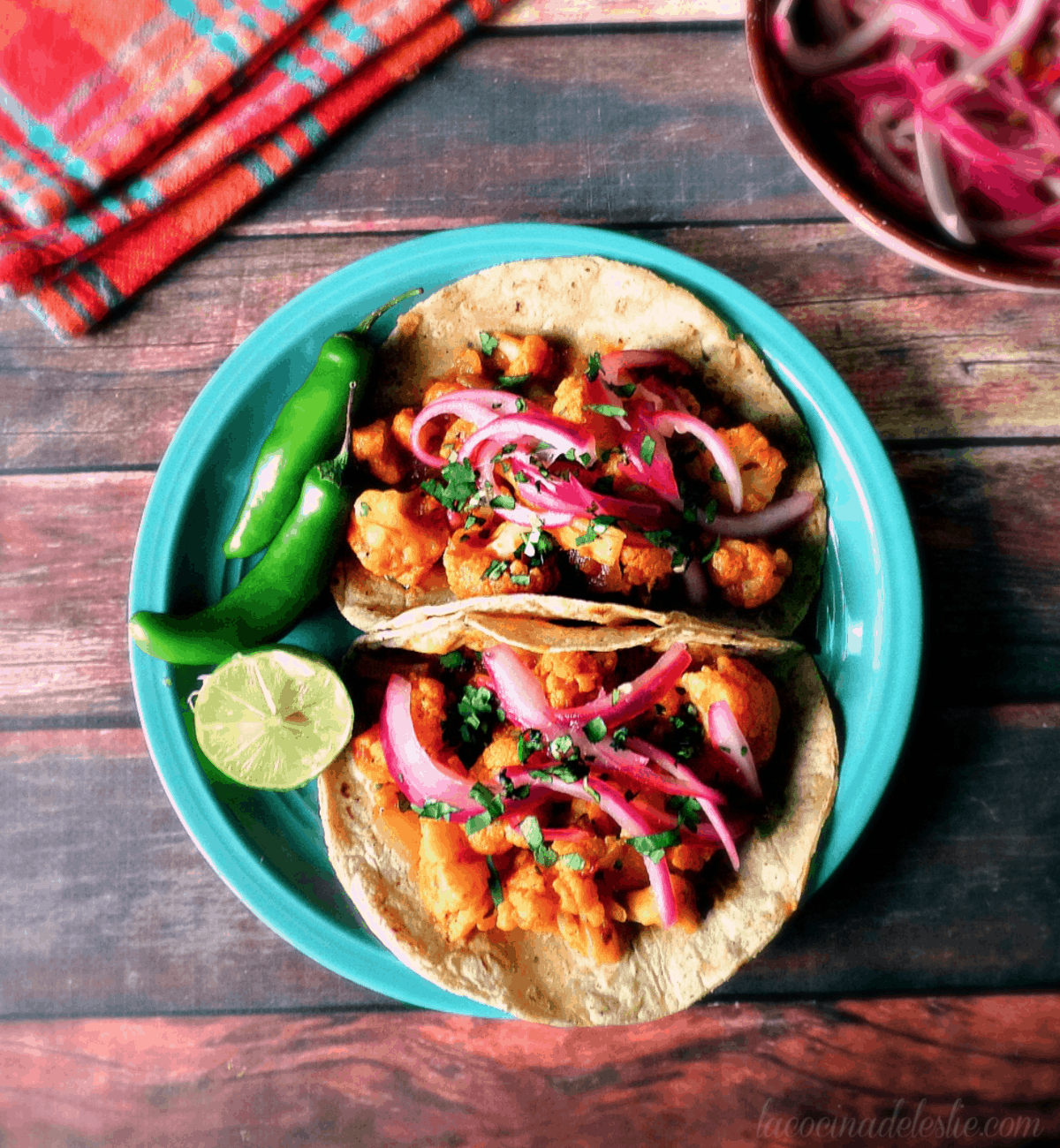 Cauliflower Tinga Tacos on a blue plate topped with pickled red onions. 