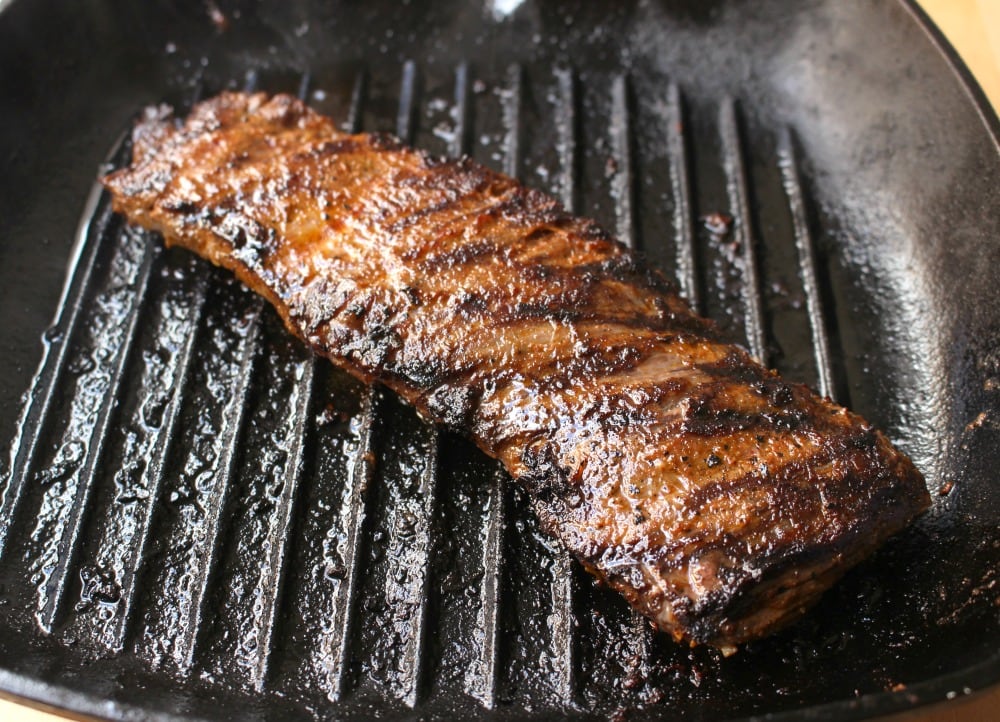 Beef grilling on a black cast iron grill skillet.