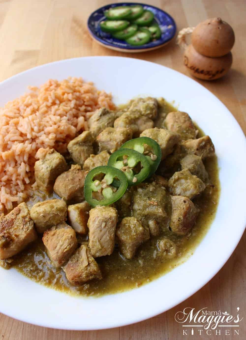 Pork Chile Verde on a white plate next to Mexican rice.