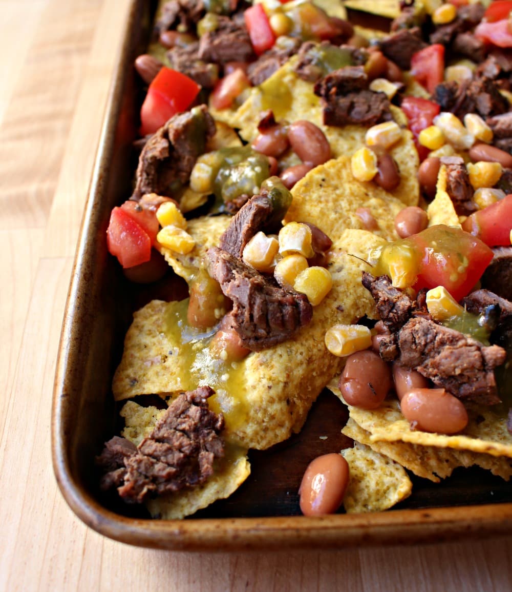 A layer of carne asada nachos minus the cheese on a wooden surface.