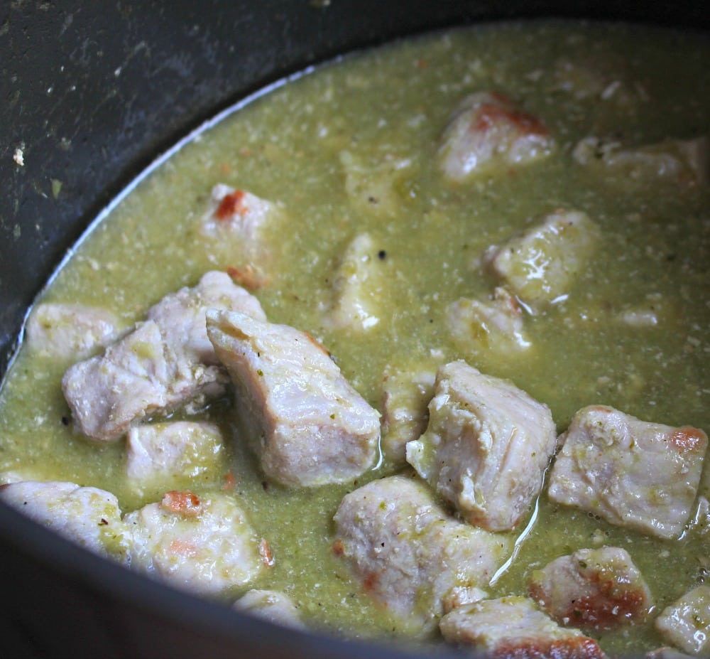 Salsa verde in a stock pot with the pork ready to cook down.