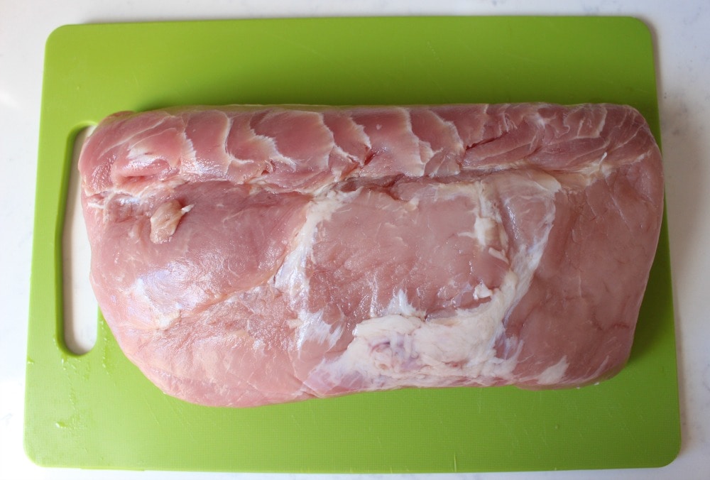 Raw pork loin on a green cutting board.