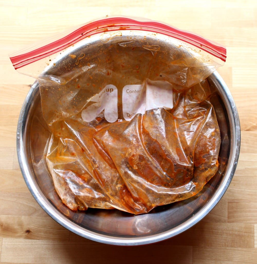 Rumba Meats beef marinating in a plastic sealed bag and in a metal bowl.