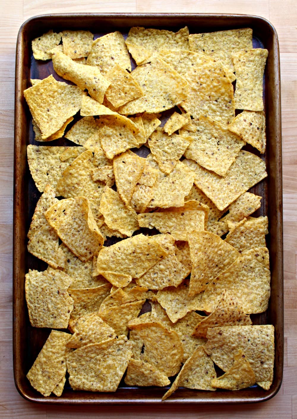Tortillas chips laid out on a sheet pan. 