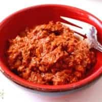 Mexican chorizo in a red bowl with a fork on the side.