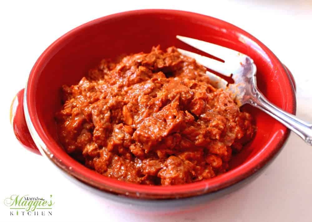 Raw Mexican sausage in a red bowl with a fork on the side.