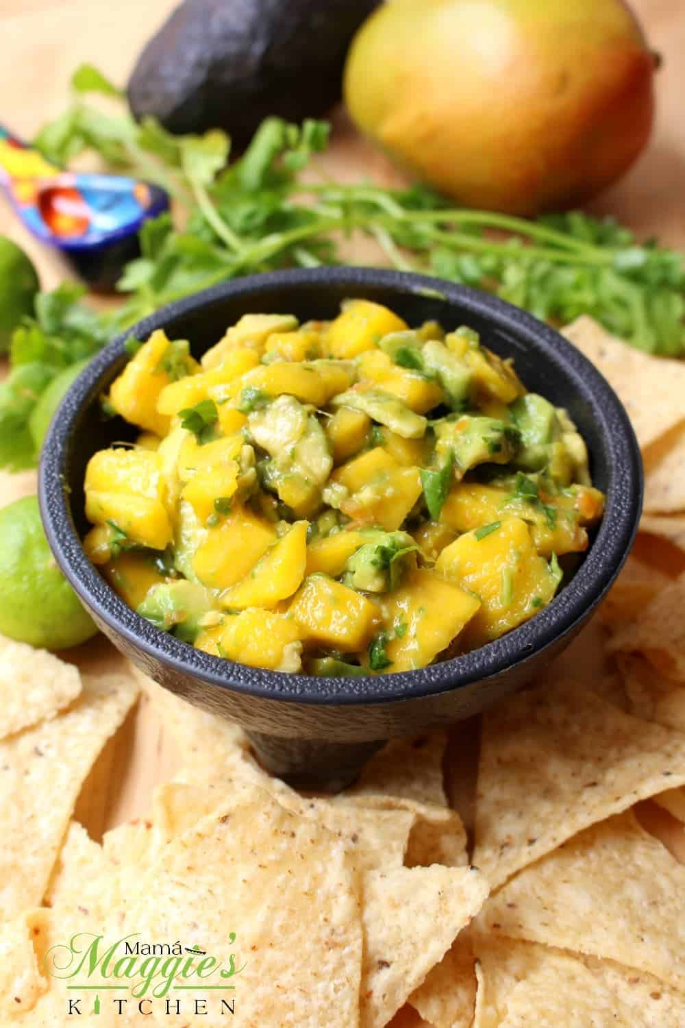 Avocado Mango Salsa in a serving bowl surrounded by chips and the ingredients.