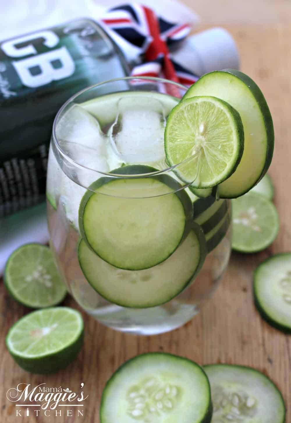 Cucumber Gin Cocktail served in a clear glass and surrounded by cucumber and lime slices. 
