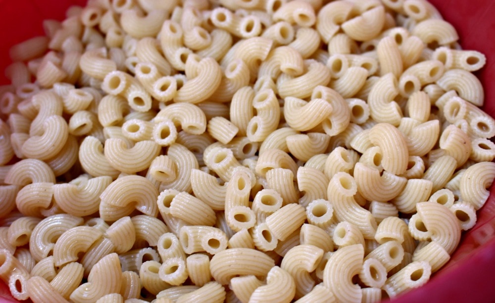 Cooked elbow macaroni pasta in a pink bowl.