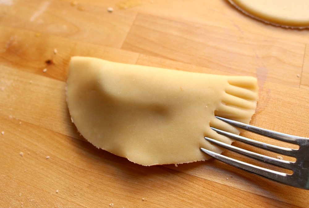 A fork sealing the edges of an empanada.