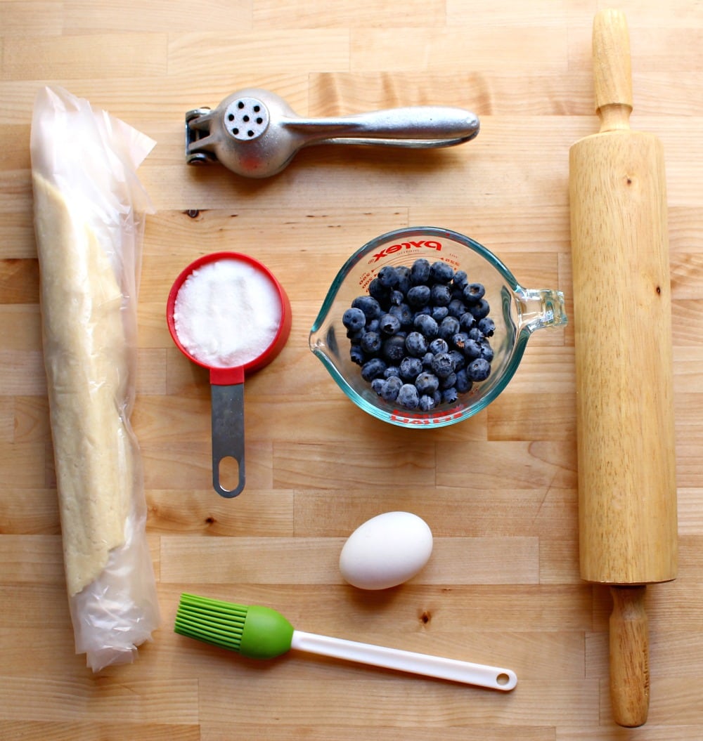 Ingredients to make blueberry empanadas spread out on a wooden surface.
