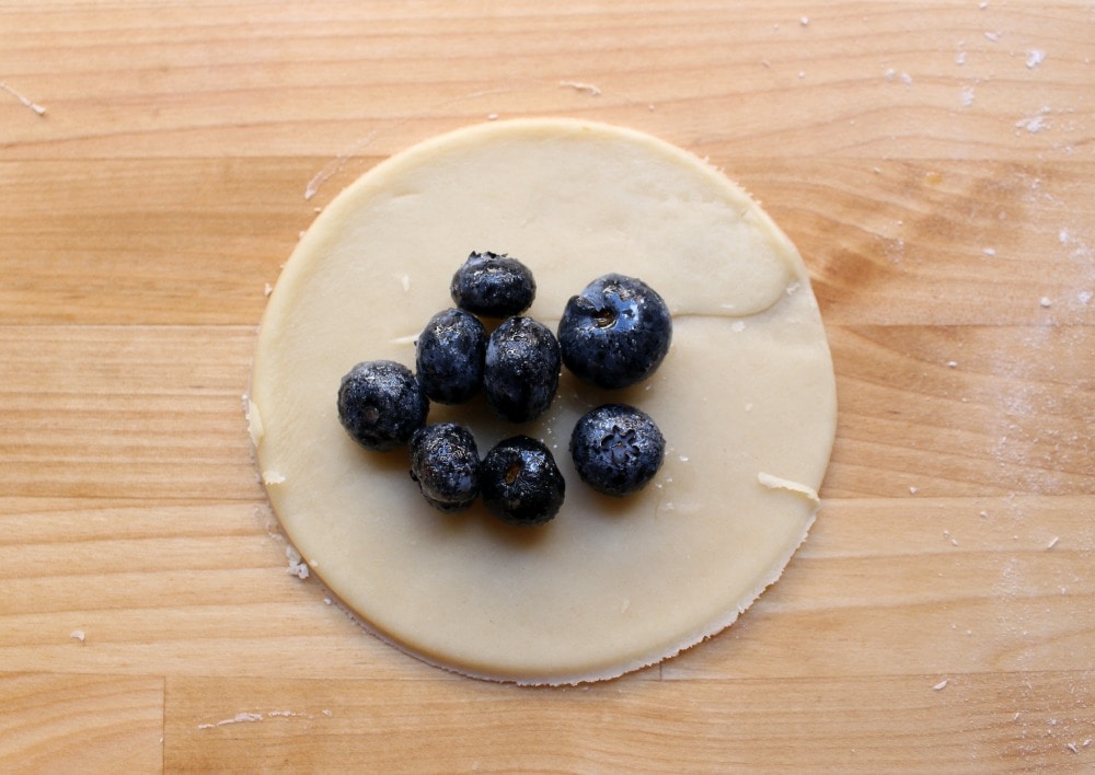 Blueberry filling in the center of a circle of pie dough. 